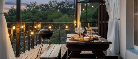Un patio al aire libre con una parrilla, una mesa de madera y luces colgantes.