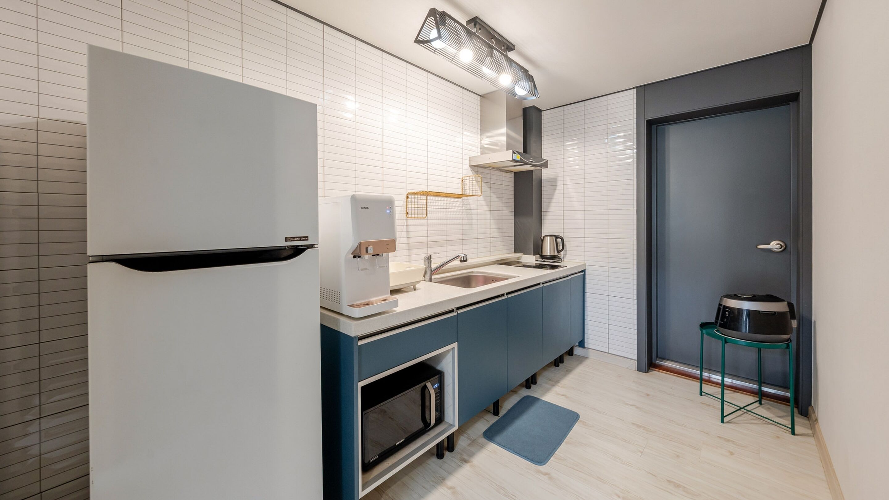 Eine moderne Küche mit integriertem Kühlschrank, Spüle, Mikrowelle und Wasserkocher.