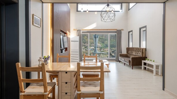 Un interior moderno con comedor, sofá y vistas a través de amplios ventanales.