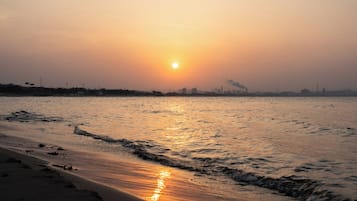 A beach with waves and a sunset.