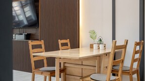 Un comedor con una mesa y sillas de madera, una planta pequeña y un farol sobre la mesa.