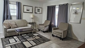 A living room with a sofa, two armchairs, a coffee table, a rug, a lamp, and framed pictures on the wall. - Private 10BR Secluded Compound, Spacious Retreat w/ Abundant Parking (Memphis)