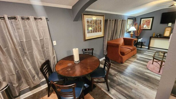 A dining area with a round wooden table, chairs, a candle, and a sofa in the background. - Private 10BR Secluded Compound, Spacious Retreat w/ Abundant Parking (Memphis)