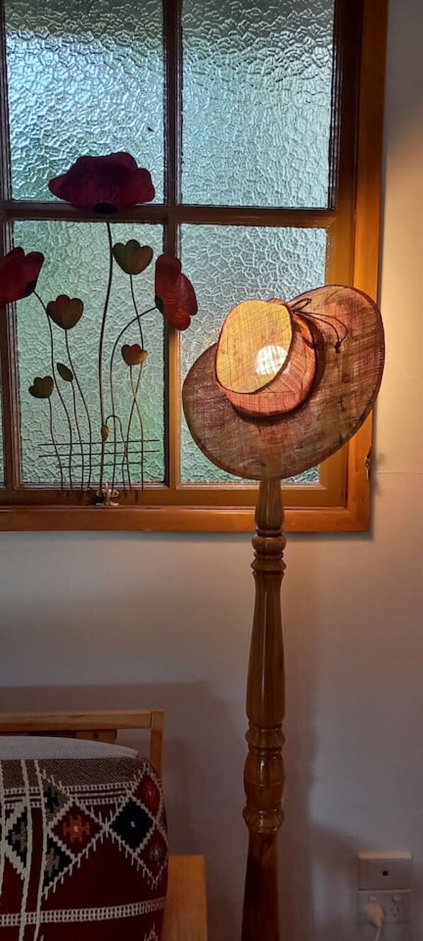 A lamp with a wooden base and a glass shade, positioned in front of a window with frosted glass panes.