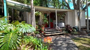 A house with a porch, potted plants, and a pathway leading to the entrance. - Quirky Cottage in Centre of Maleny Walk Everywhere (Maleny)