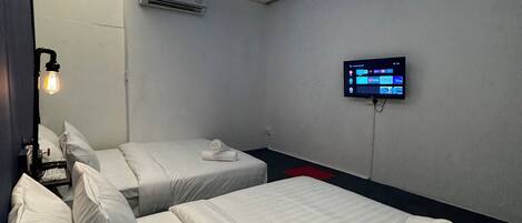 A hotel room with two beds, a flat-screen TV mounted on the wall, and a ceiling with recessed lighting.