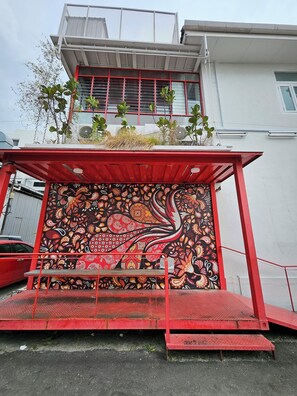 A building with a red awning and a mural with paisley patterns. - The Harbour (George Town)