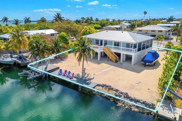 A beachfront property with a dock, a pool area with lounge chairs, and a building with a balcony.