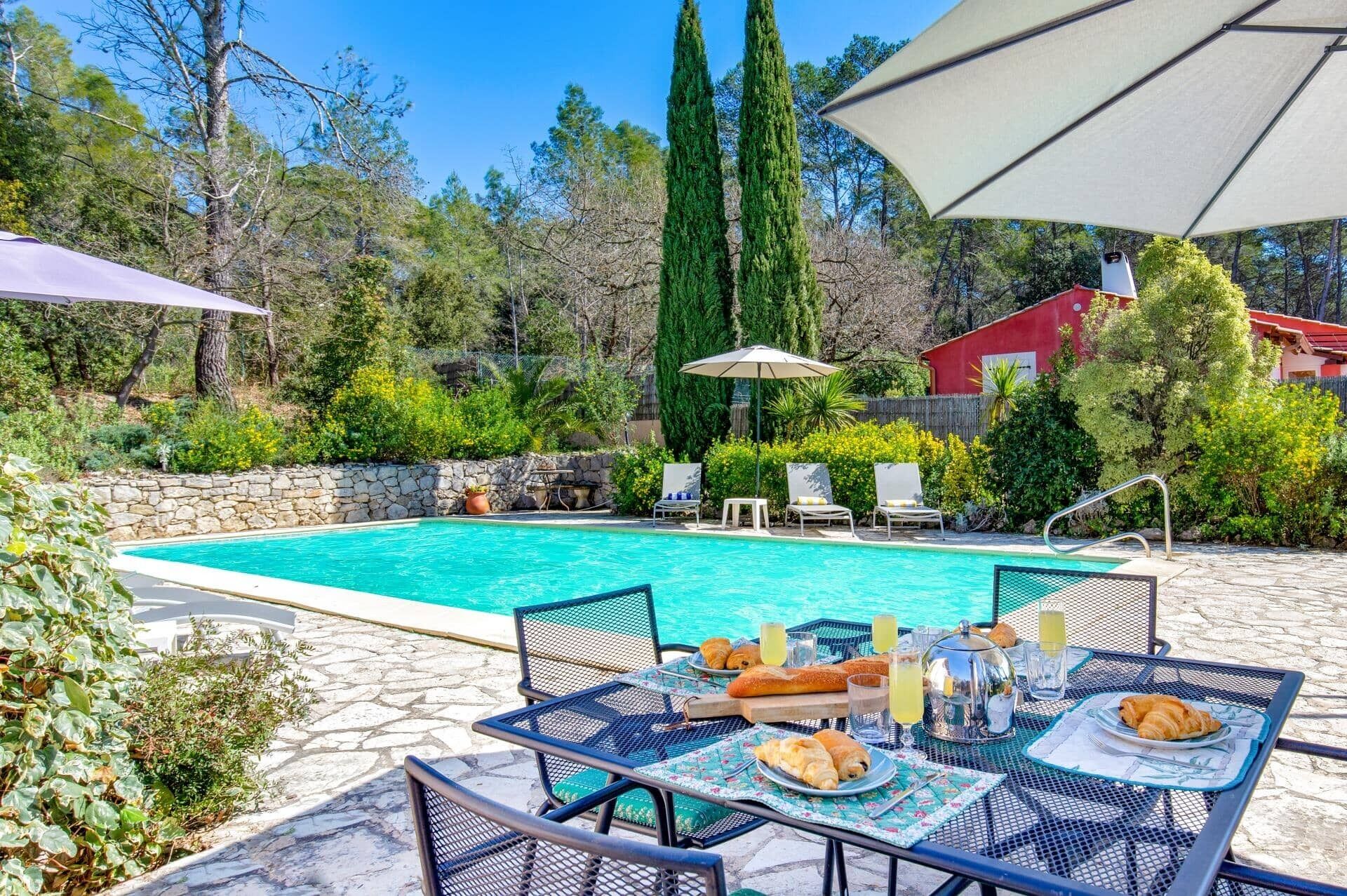 A pool area with lounge chairs and a table set for breakfast.