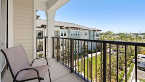 A balcony with a chair, a railing, and a view of neighboring buildings. - The Garden Luxe Retreat (Winter Garden)