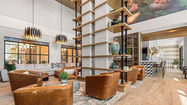 A spacious living area with a high ceiling, a modern staircase, and a dining area with a bar. - Winter Garden Charm, Near Disney (Winter Garden)