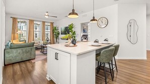 A modern kitchen with a central island, pendant lighting, and a dining area with bar stools. - Winter Garden Charm, Near Disney (Winter Garden)