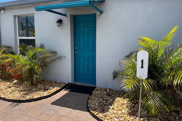 A building with a blue door, a numbered sign, and a pathway leading to the entrance.