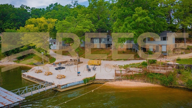 A lakeside property with a dock, outdoor seating, and a small building. - Beach Cabin #1, Private/Shared Beach - Cabin #1 (Lake Ozark)
