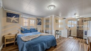 Quarto com cama grande, piso de madeira, mesa de cabeceira pequena e uma janela.