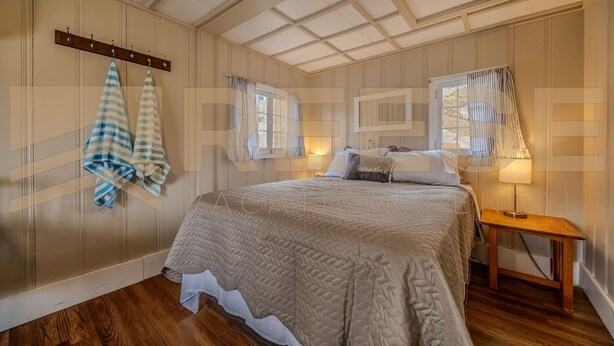 Een slaapkamer met een groot bed, een houten nachtkastje en een raam met gordijnen.