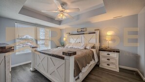 A bedroom with a bed, a nightstand, a dresser, and a ceiling fan. - Classic Lakeside Home (Lake Ozark)