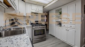 A modern kitchen with white cabinets, a stainless steel sink, and a built-in oven. - Classic Lakeside Home (Lake Ozark)