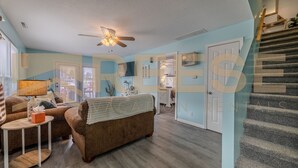A spacious living room with a sofa, a coffee table, and a ceiling fan. - Classic Lakeside Home (Lake Ozark)