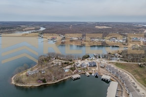 An aerial view of a lakeside property with a marina, buildings, and a road.