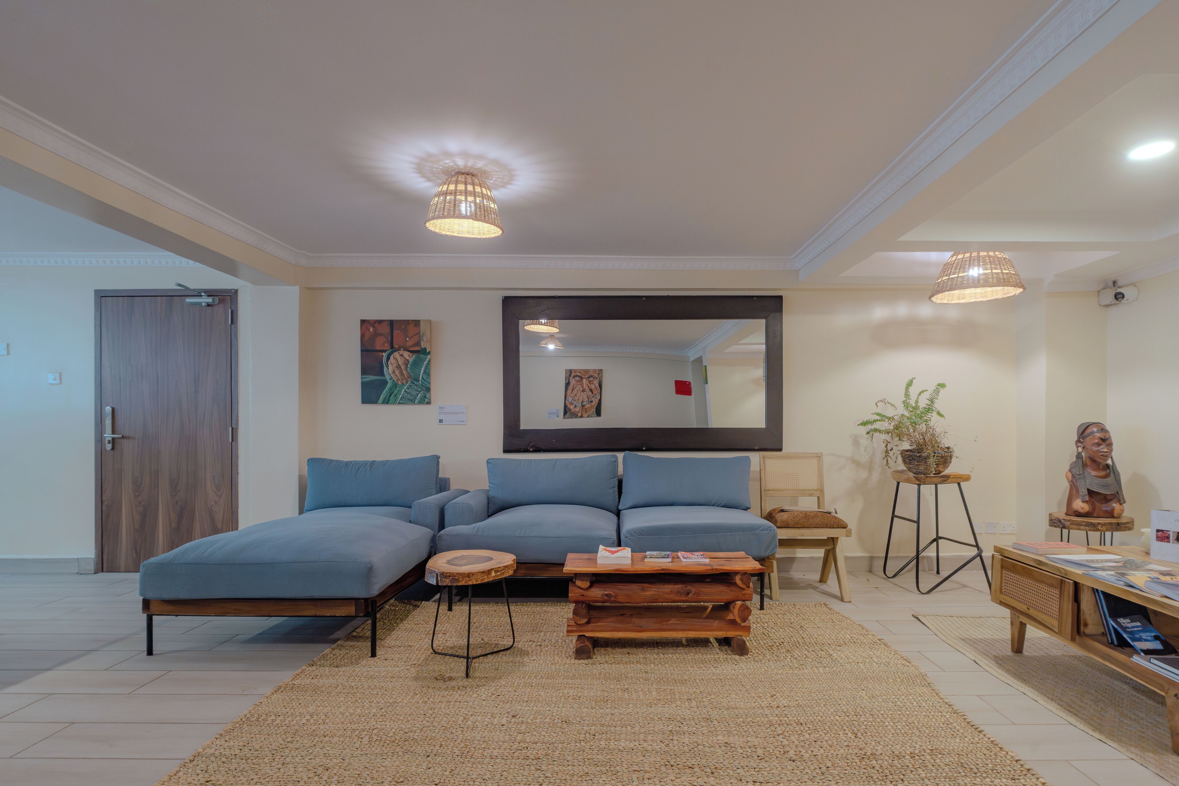 A modern living room with a sectional sofa, a wooden coffee table, a small side table, and a large mirror on the wall.