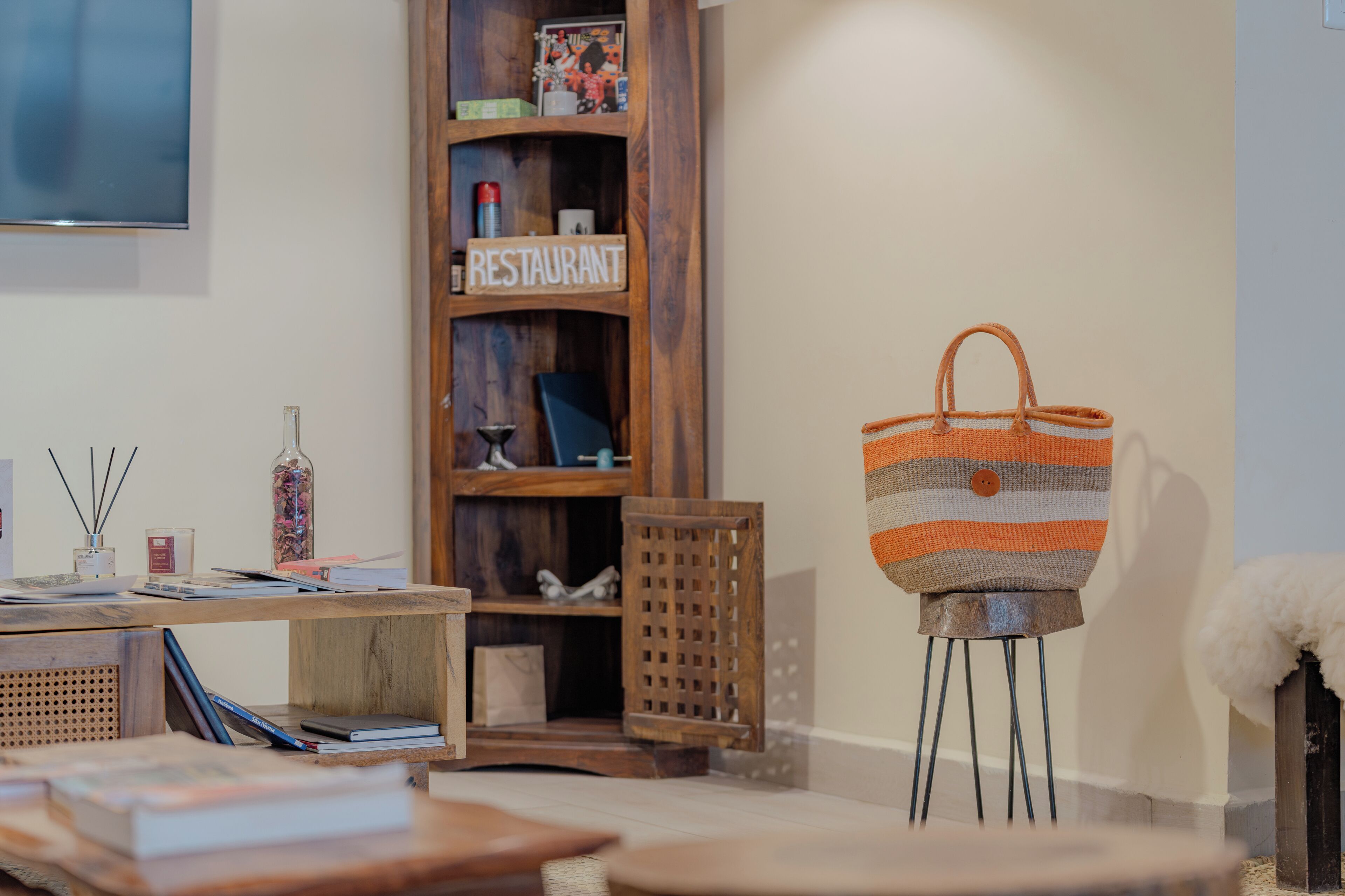 Une pièce avec une bibliothèque en bois, un sac à rayures posé sur un présentoir et un téléviseur accroché au mur.