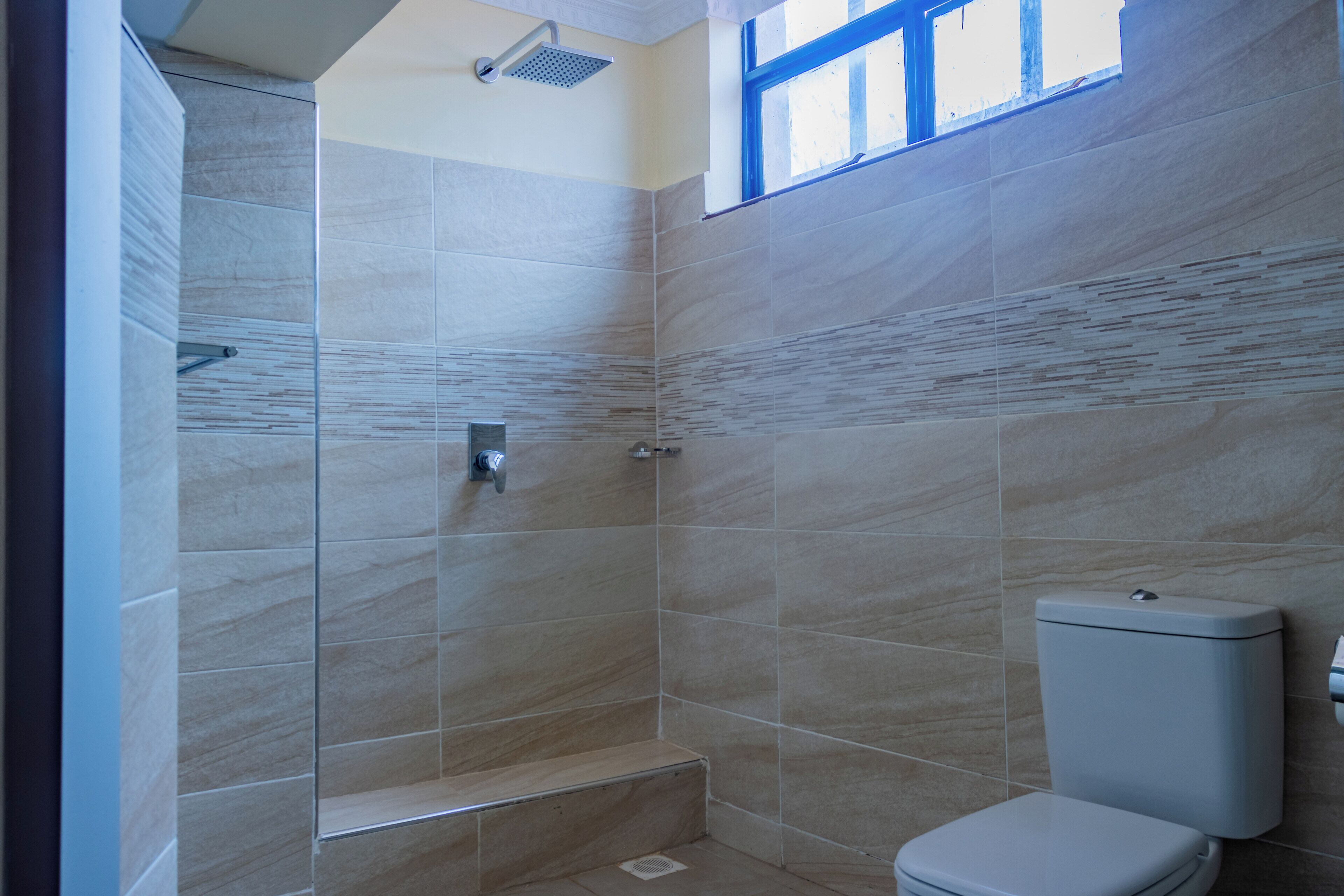 A bathroom with a shower, toilet, and a window.