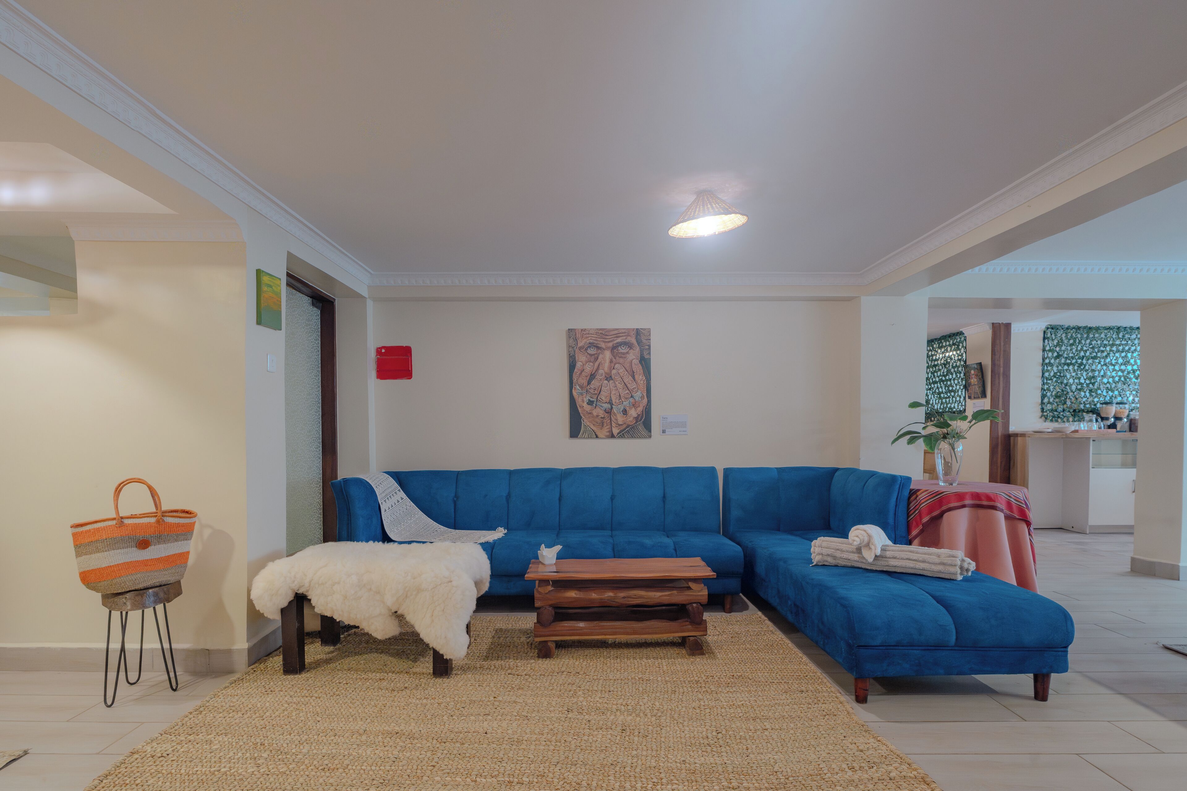 Ein Wohnzimmer mit einem blauen Sofa, einem weißen Sessel, einem Holztisch und einem gewebten Teppich.