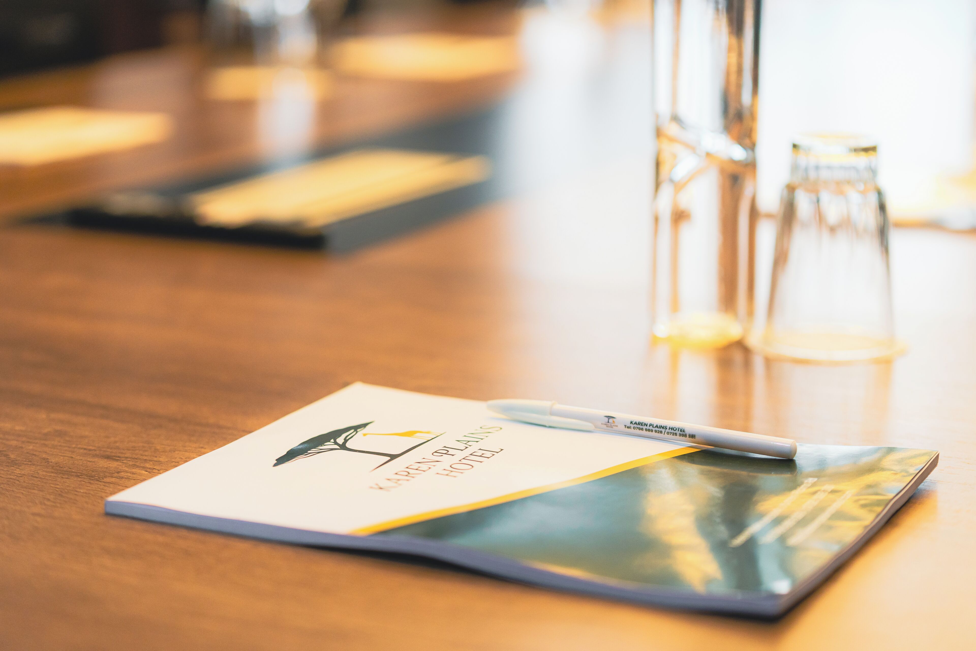 A hotel brochure on a table with a pen, a glass bottle, and a glass carafe.