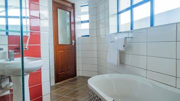 A bathroom with a white sink, a wooden door, and a large bathtub.