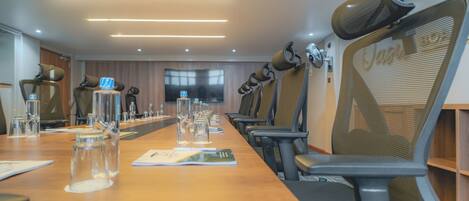 Une salle de conférence avec une longue table, des chaises et un écran de télévision.