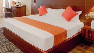 Una habitación de hotel con una cama grande, cabecera de madera, mesitas de noche, un escritorio y una silla.