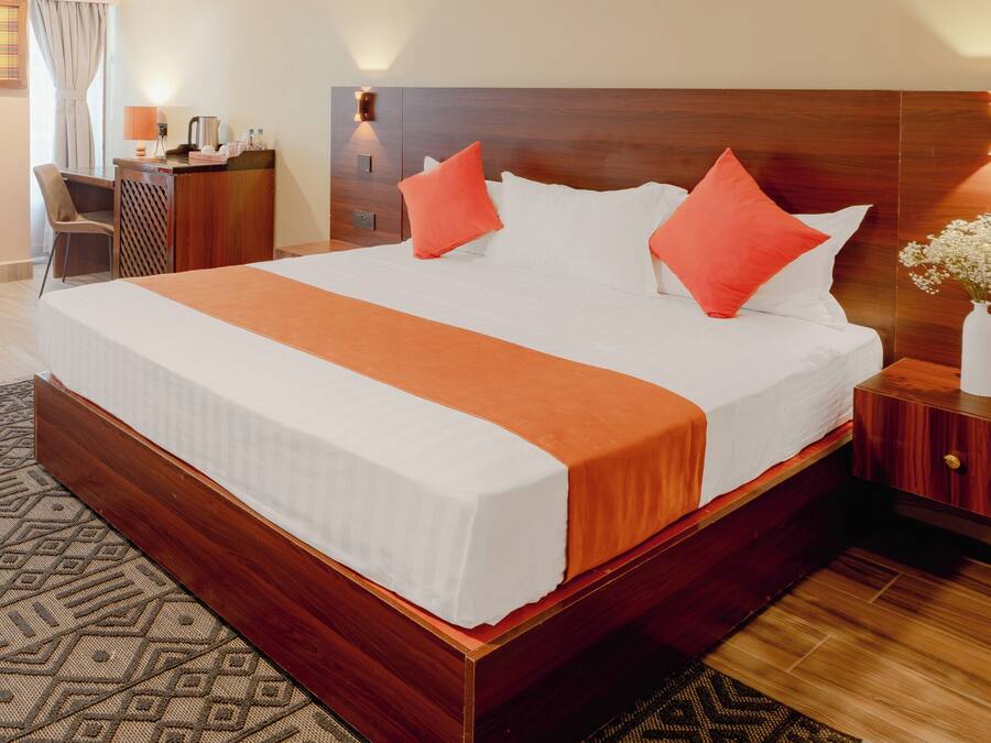 Una habitación de hotel con una cama grande, cabecera de madera, mesitas de noche, un escritorio y una silla.