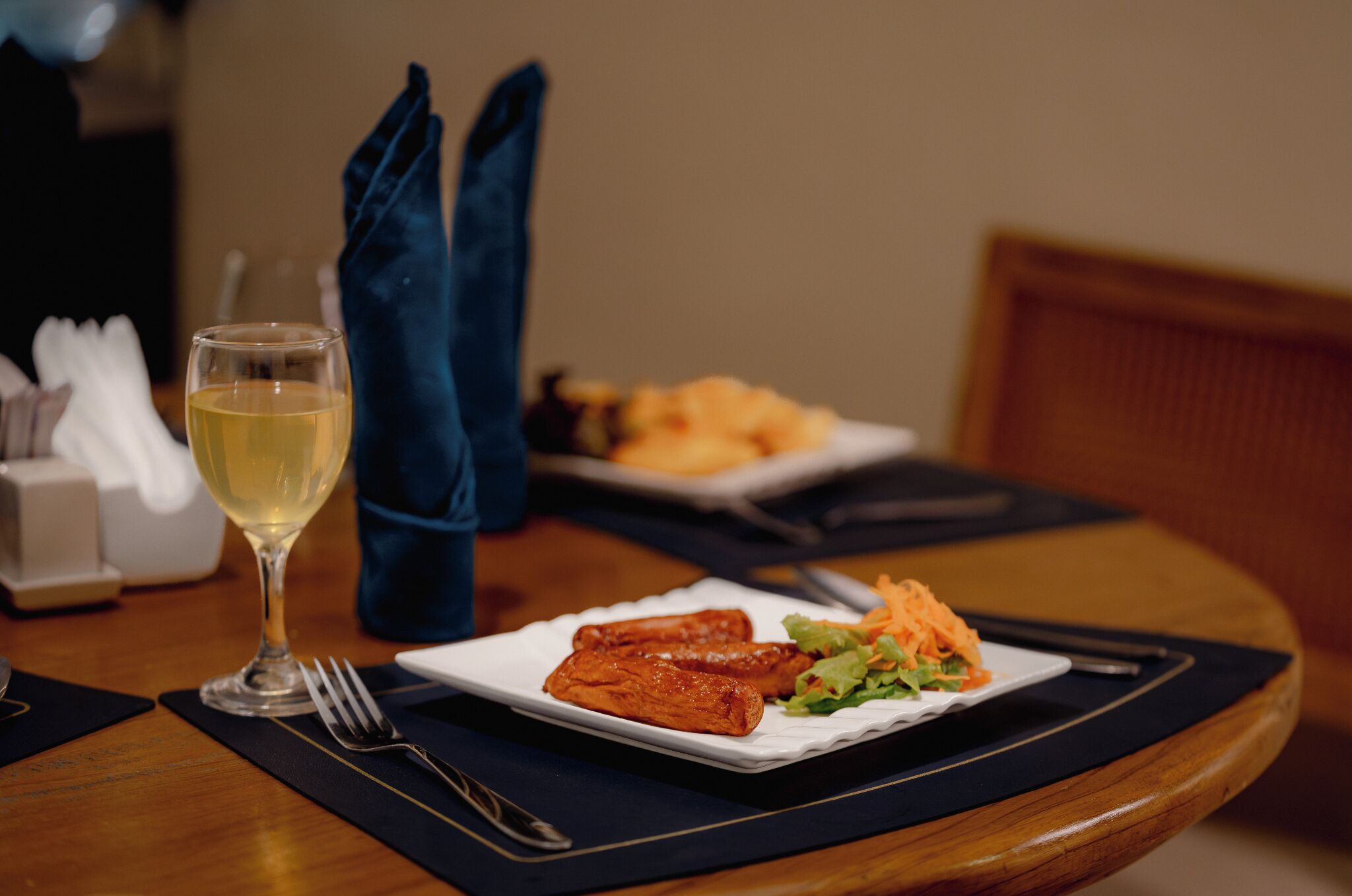 Une table à manger avec une assiette de nourriture, un verre de vin et une serviette.