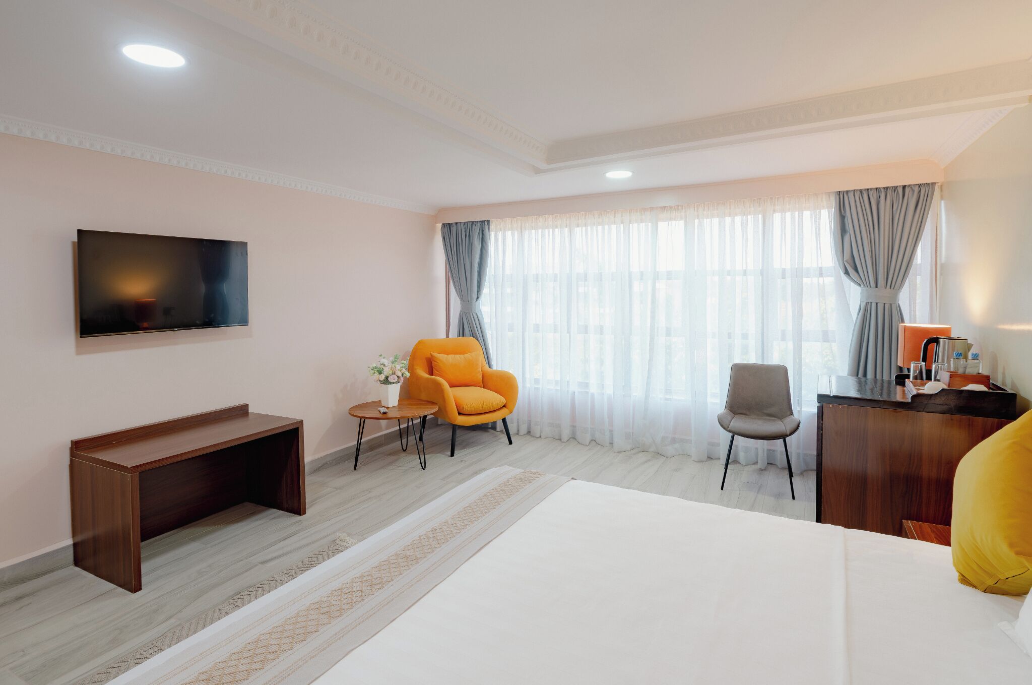 A hotel room with a bed, a desk, a TV, and two chairs.