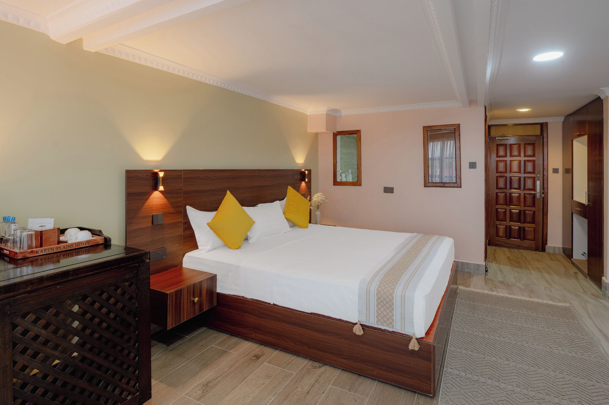 Une chambre d’hôtel avec un lit en bois, une table de chevet, un miroir et une armoire en bois.