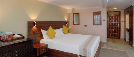 A hotel room with a wooden bed, a nightstand, a mirror, and a wooden wardrobe.