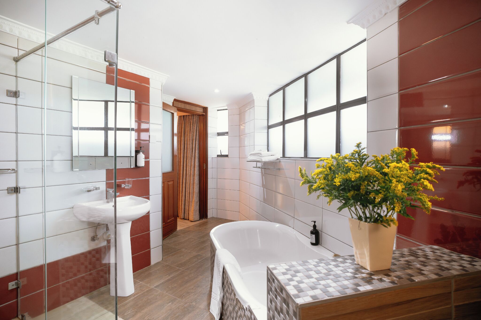 A modern bathroom with a glass shower enclosure, a freestanding bathtub, a sink, and a mirror.