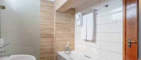 Une salle de bain moderne avec une douche à parois de verre, un lavabo blanc, une baignoire et une porte en bois.