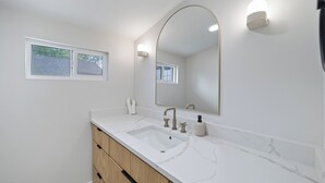 Une salle de bain avec un meuble-lavabo blanc, un double vasque et un grand miroir.