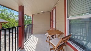 Un balcon abrité avec une table et des chaises, une fenêtre et une vue sur la verdure.