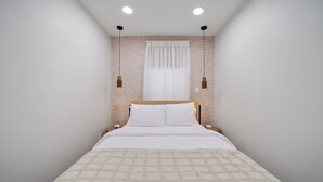Une chambre à coucher bien rangée, avec un lit, des tables de chevet et une fenêtre avec des rideaux.