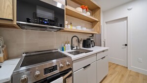 Une cuisine moderne dotée d’appareils électroménagers en acier inoxydable, de meubles blancs et d’étagères en bois.