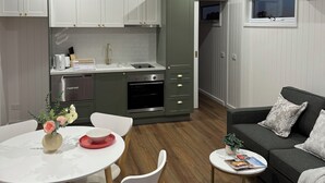 A modern kitchen with white cabinets, a built-in oven, and a ceiling fan. - Kingdom Cottages (Gulgong)