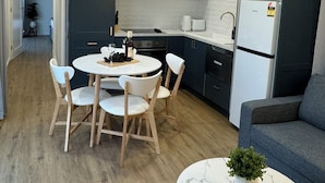 A modern kitchen with white cabinets, a black refrigerator, and a dining area with a round table and chairs. - Kingdom Cottages (Gulgong)