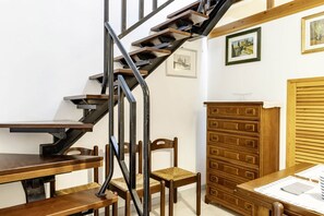 A staircase with a wooden finish, a wooden chair, a wooden dresser, and a framed picture on the wall.
