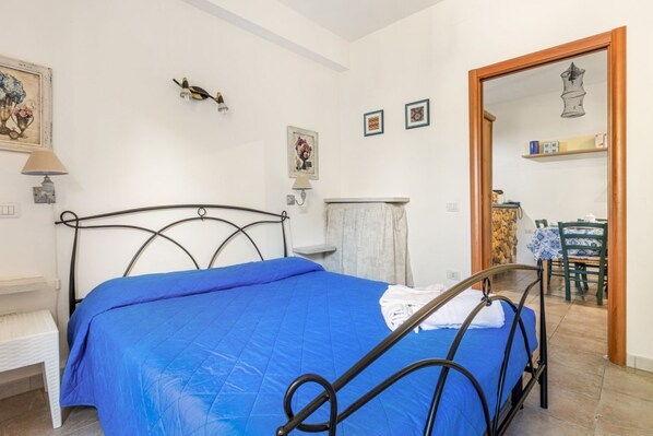 A bedroom with a bed, a chair, a table, and a mirror.