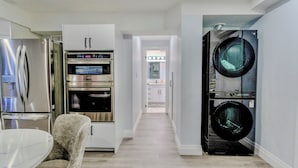 A modern kitchen with stainless steel appliances, a marble dining table, and a built-in washer and dryer. - Luxurious Unit in Hyde Park (London)