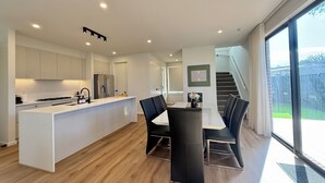 A modern kitchen with white cabinetry, a central island, and a dining area with black chairs. - Aalto Retreat 3: Chic & Modern, Close 2 Everything (Rosebud)