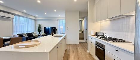 A modern kitchen with a central island, built-in appliances, and a view into the dining area.